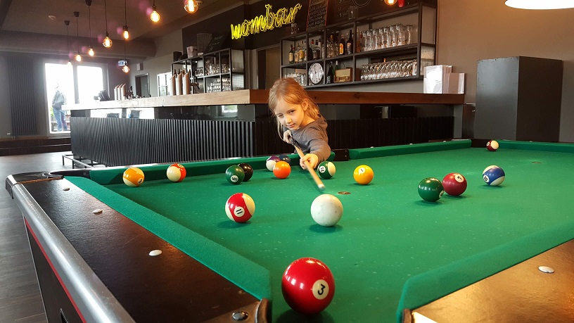 A girl playing pool in a hostel